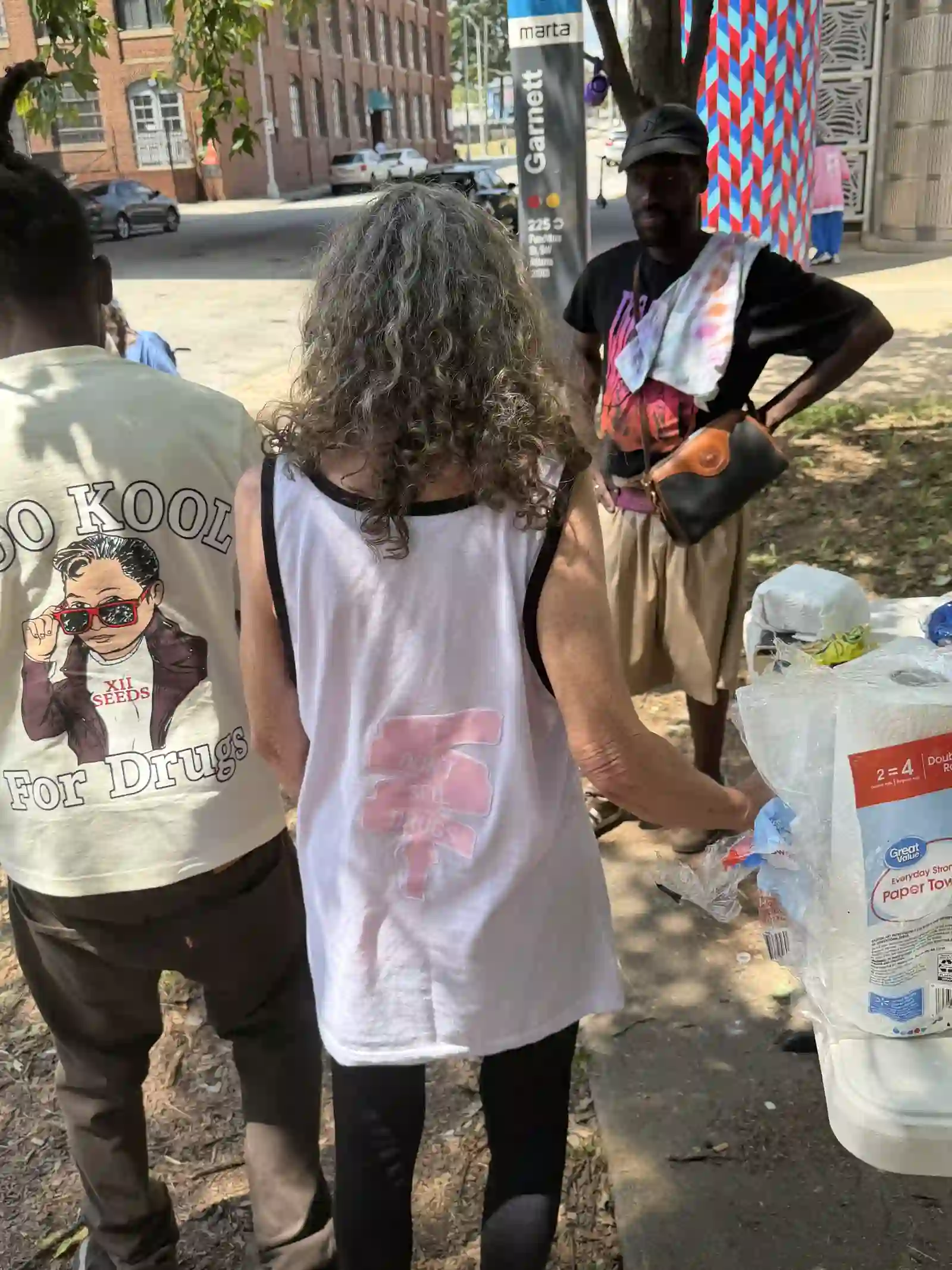 Man and woman standing together, backs to camera, near a parking garage
