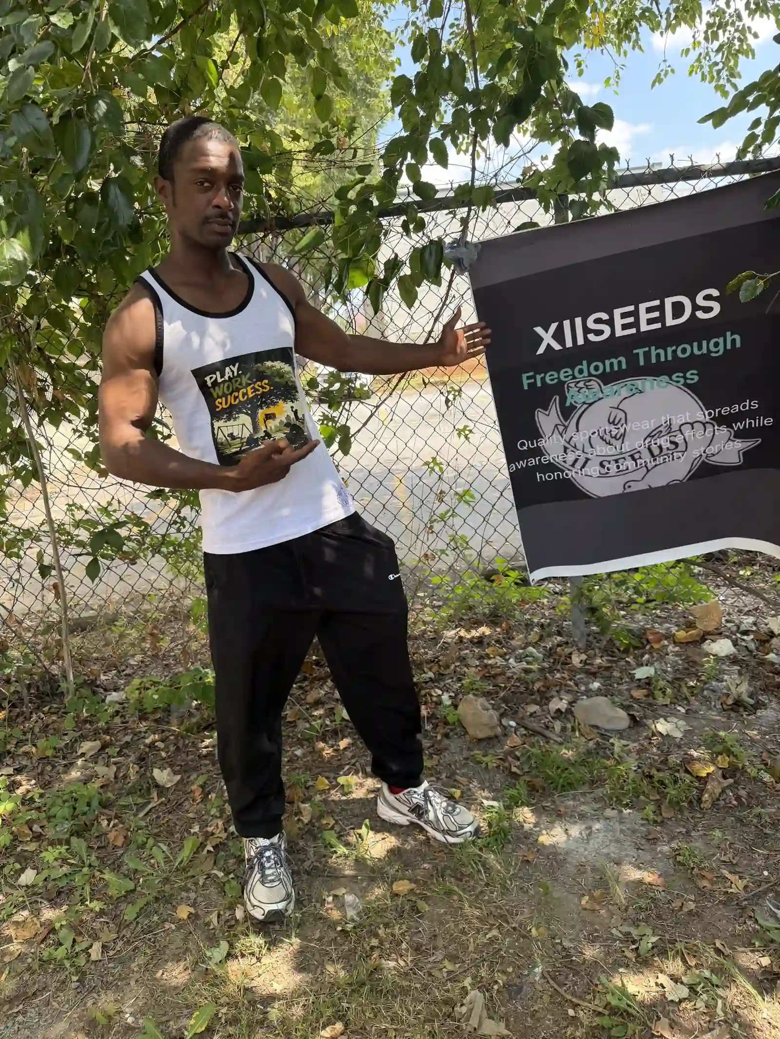 Volunteer wearing a white XIISEEDS tank top by the banner