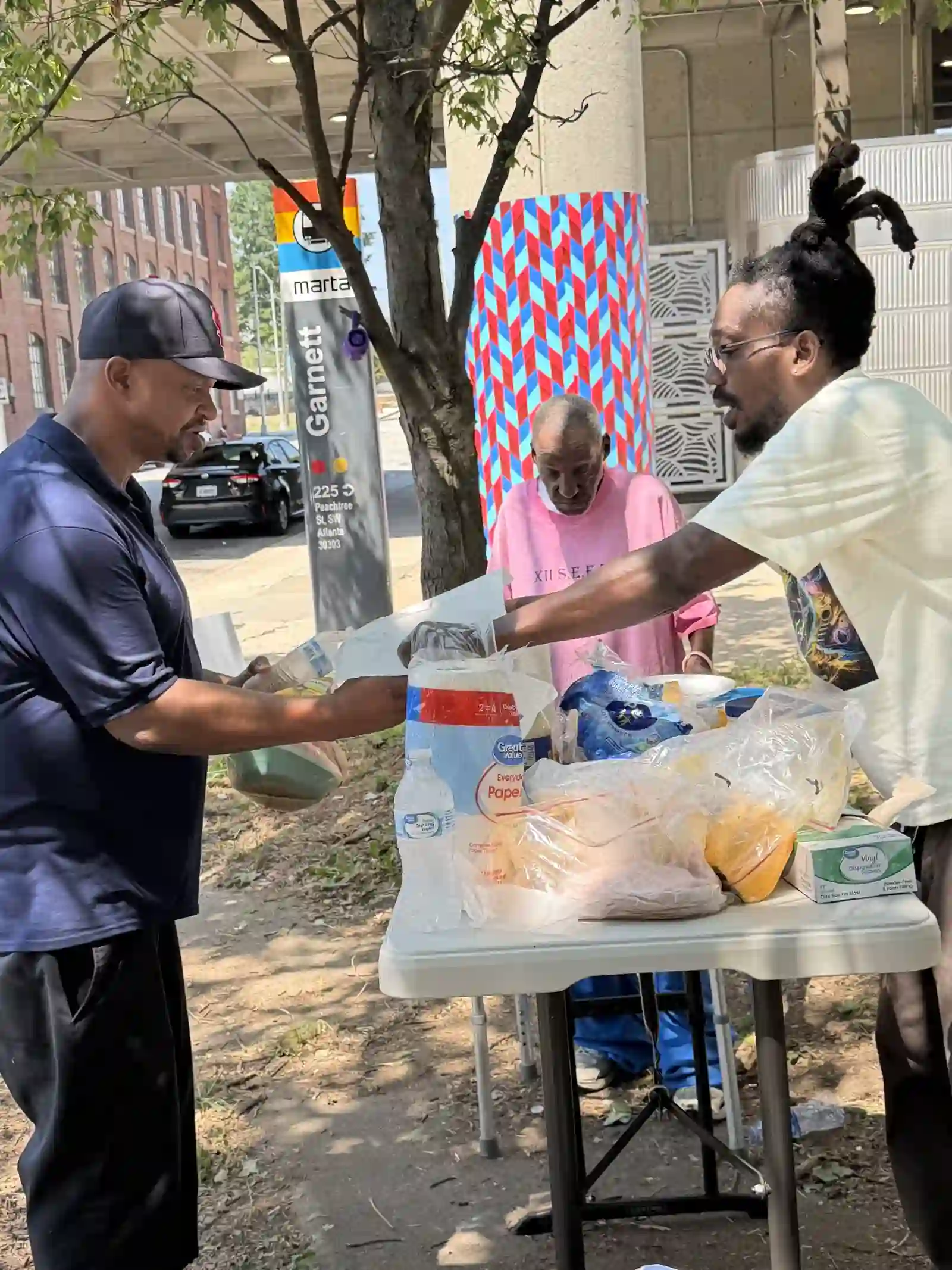 Volunteer handing a bag of supplies to a man at the outreach table