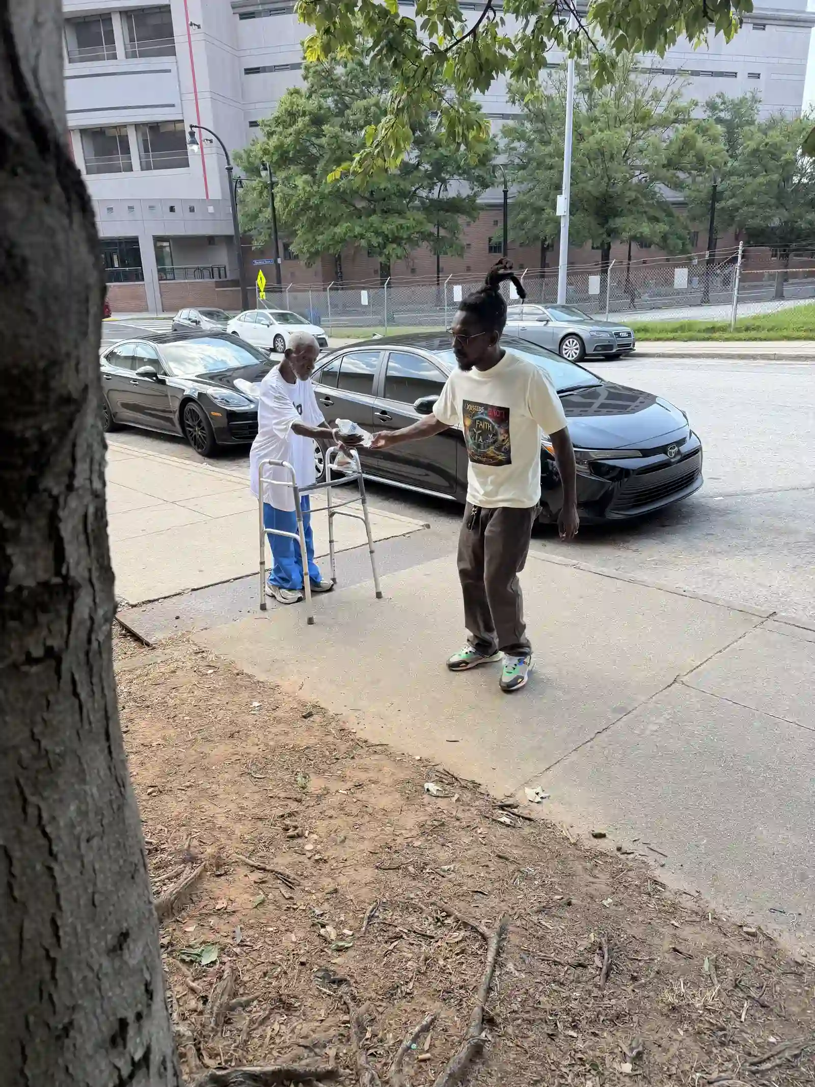 Two men walking down the sidewalk, one using a walker