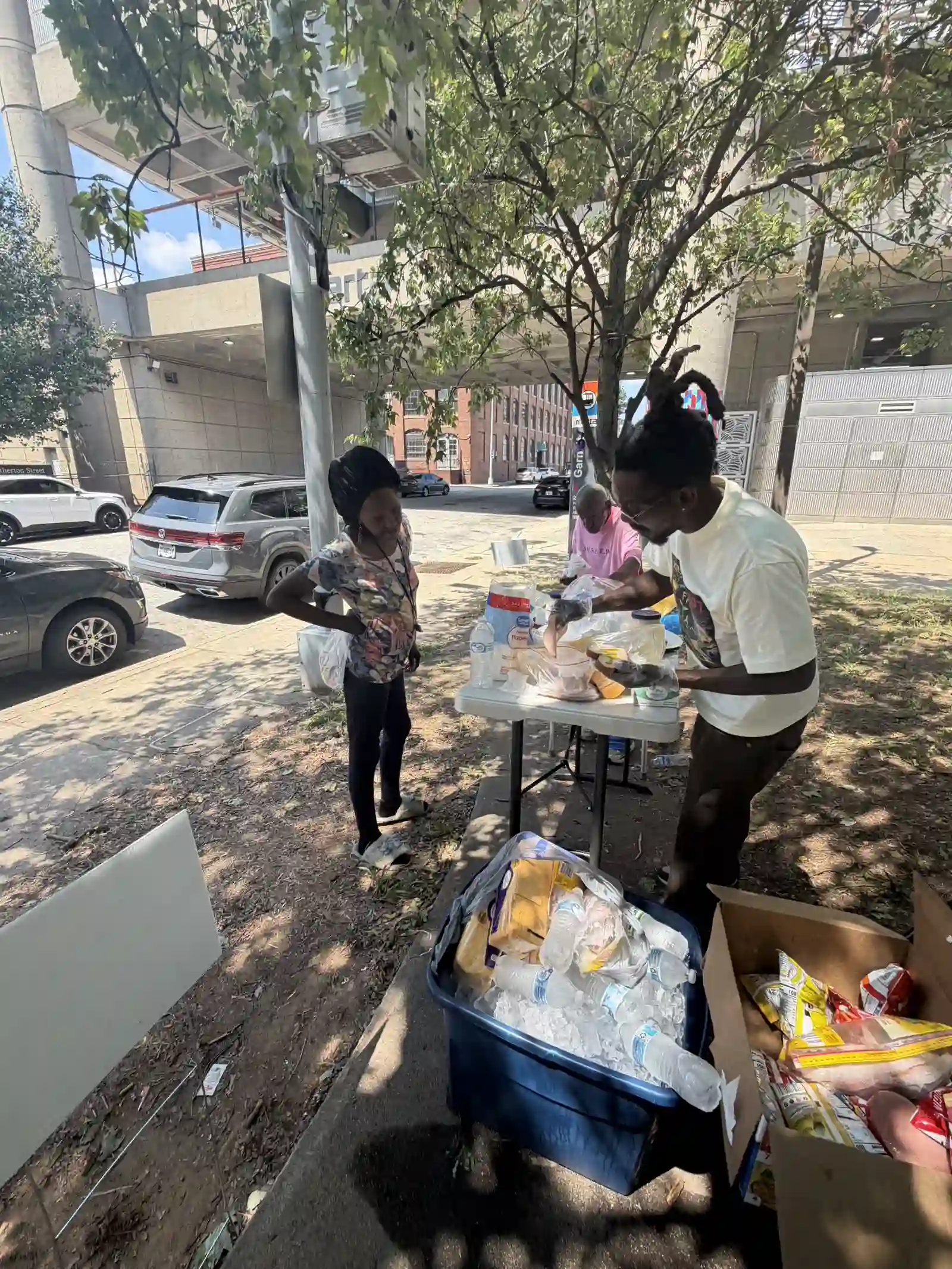 Volunteers greeting a community member at the supply table