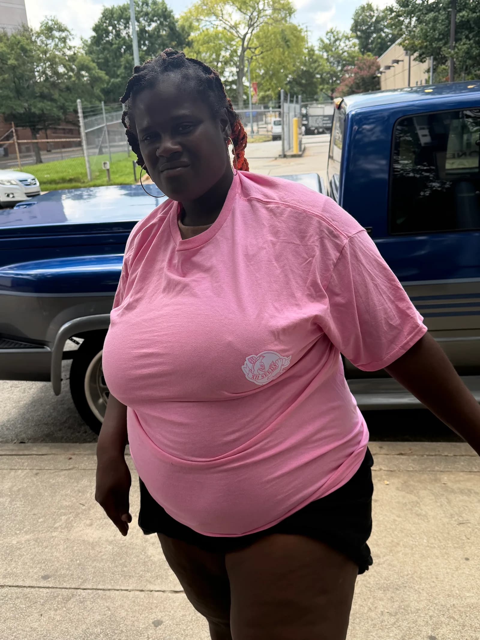 Woman wearing an XIISEEDS shirt standing on the sidewalk