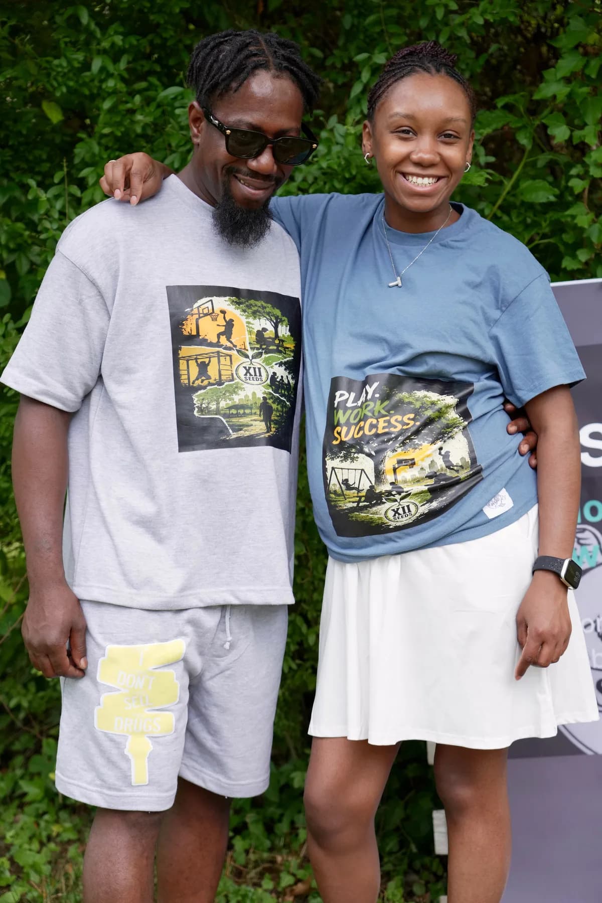 Couple wearing XII SEEDS apparel, man in a gray graphic tee and woman in the 'Play. Work. Success.' tee