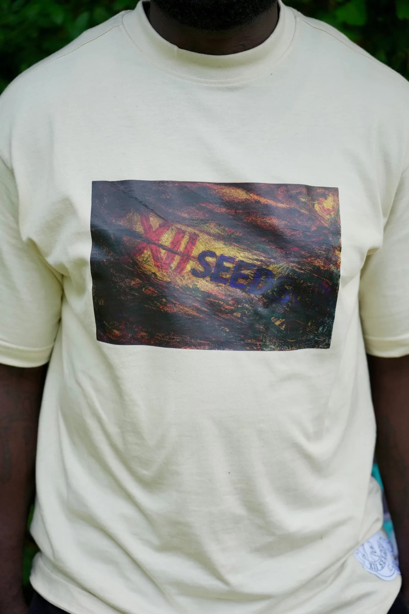 Man wearing a cream XII SEEDS graphic tee outdoors