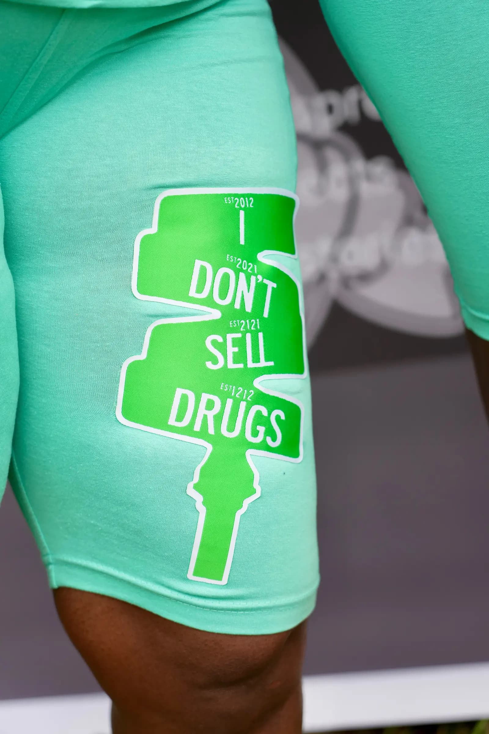 Close-up of the 'I Don't Sell Drugs' graphic on mint XII SEEDS biker shorts