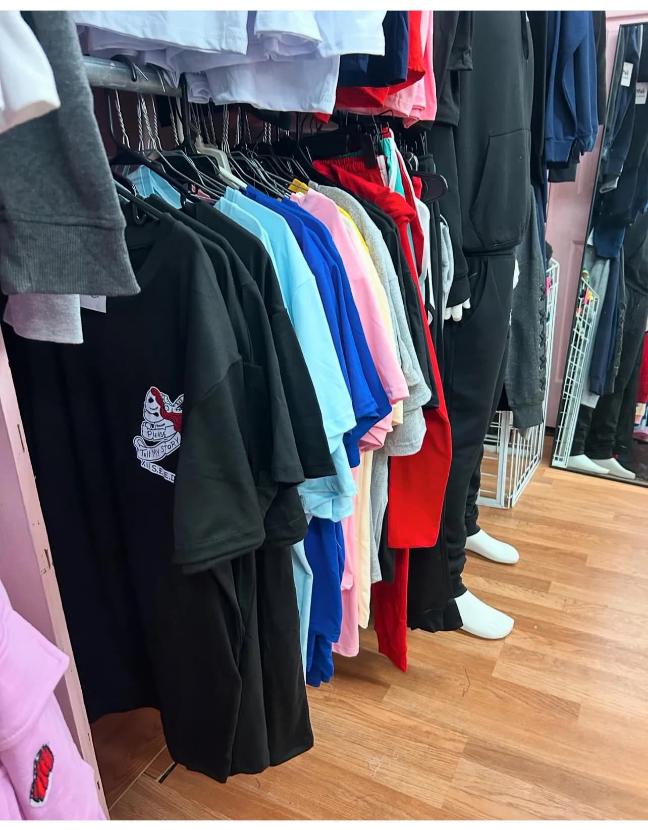 Rack of "Please Tell My Story" tees in assorted colors at the XII SEEDS store