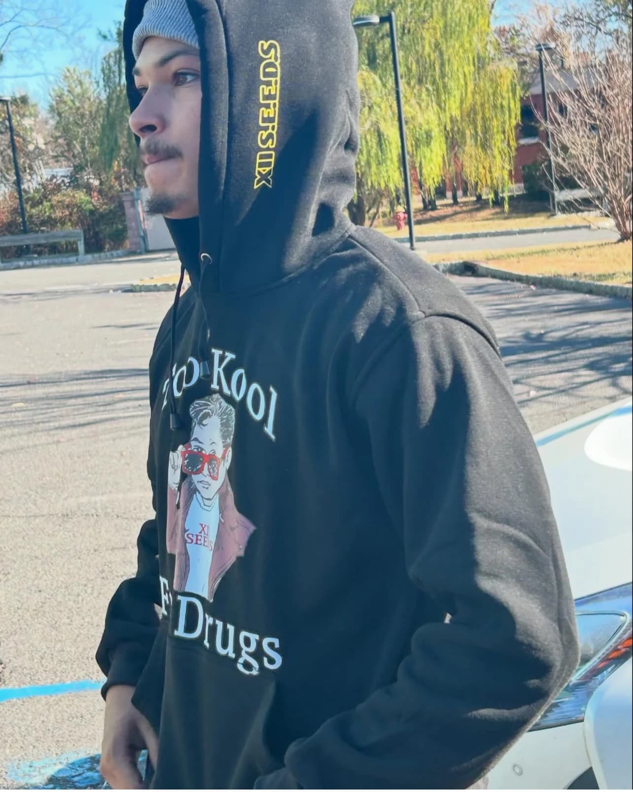 Man wearing a black "Too Kool For Drugs" hoodie outdoors